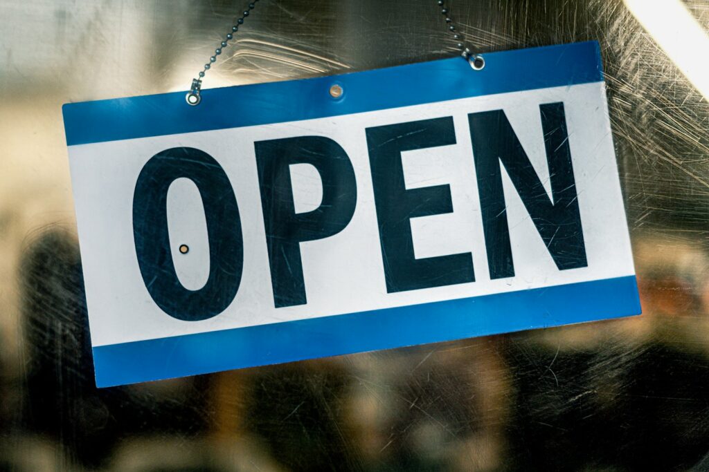 Open sign hanging on a glass shop door, showing the store is trading