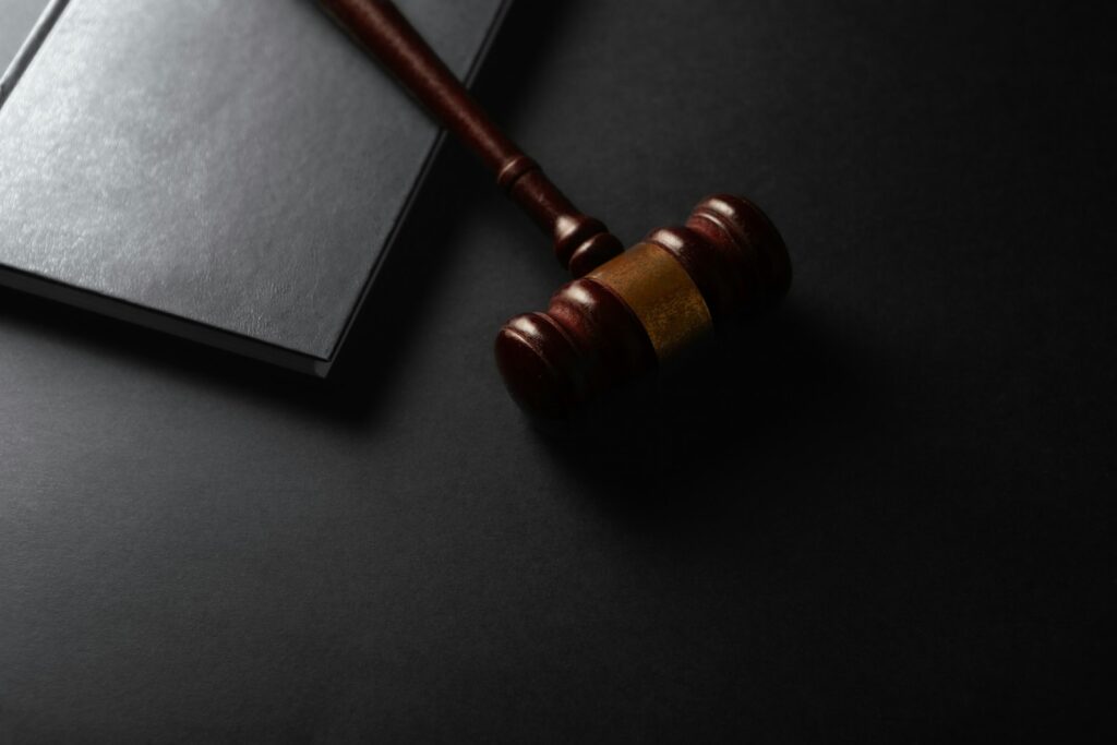 Wooden gavel resting on a dark surface beside a book, representing small claims court proceedings and litigation funding